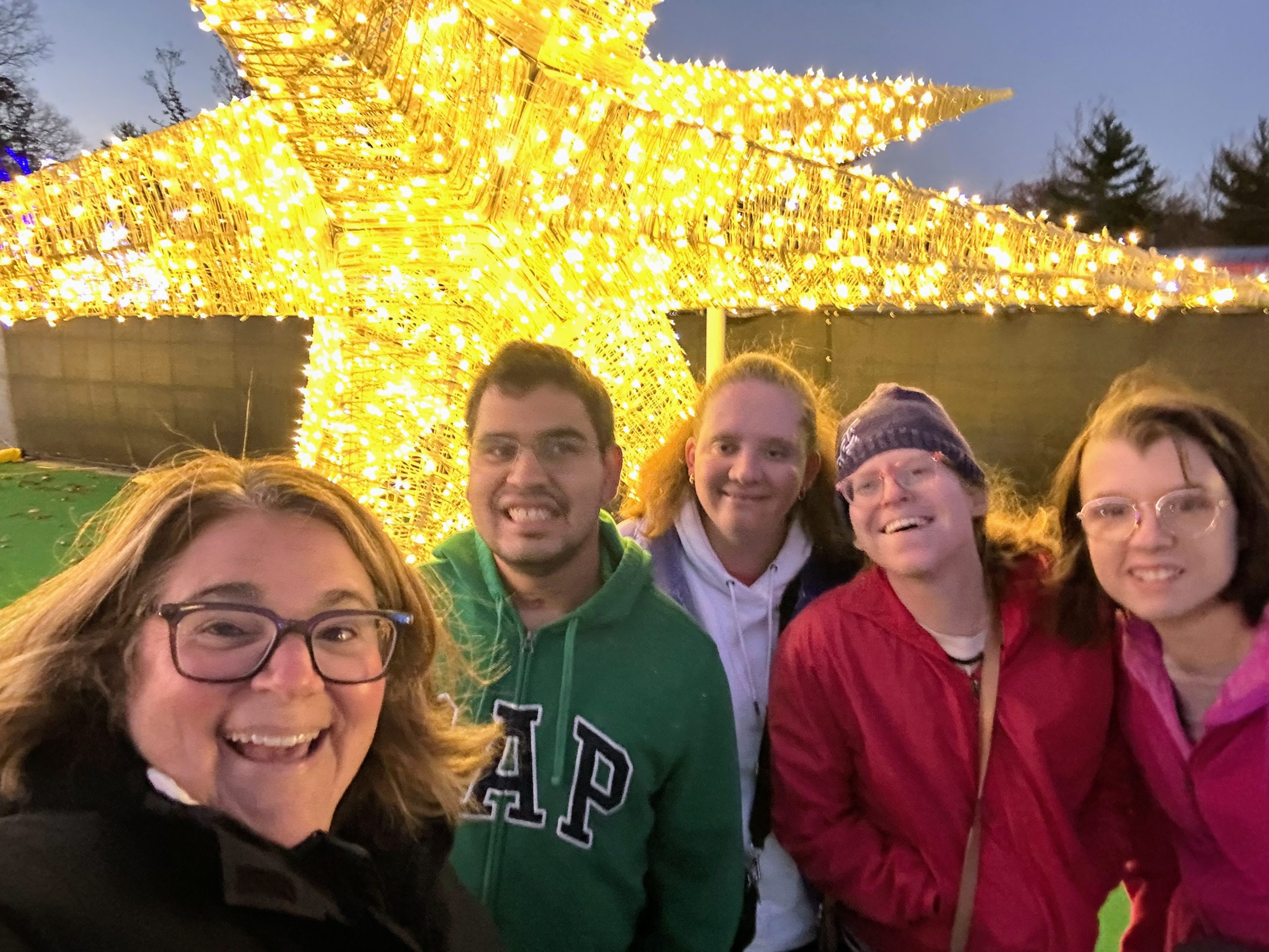 Five people standing in front of a light up star.
